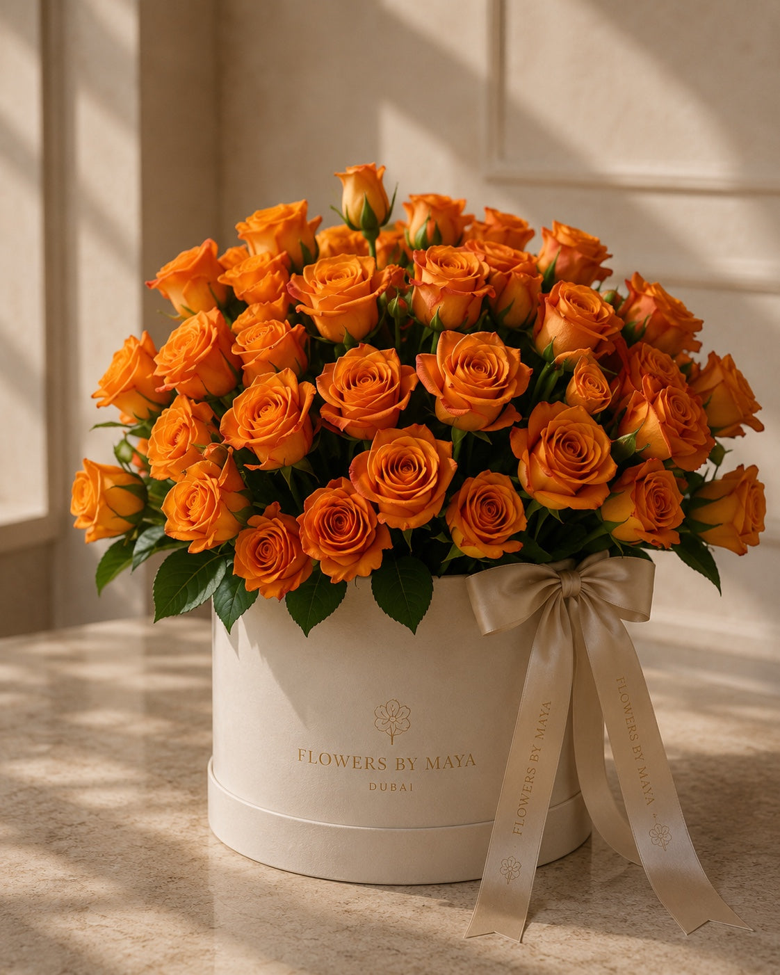 Autumn Flame by Flowers By Maya, orange roses in a cream suede hat box with champagne ribbon