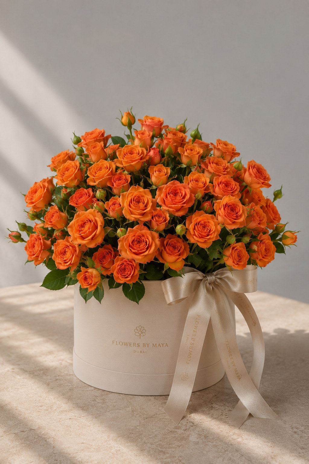 Orange Spray Rose Hat Box by Flowers By Maya, vivid orange spray roses in a cream suede hat box with champagne ribbon