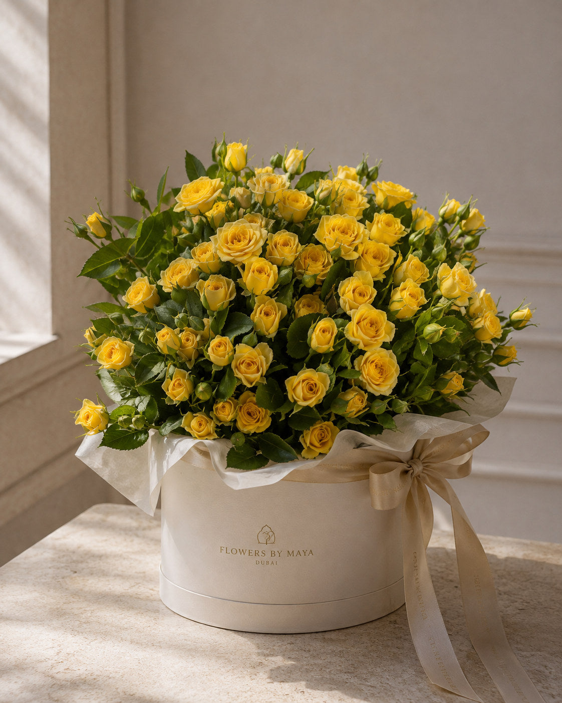 Yellow Spray Rose Hat Box by Flowers By Maya, yellow spray roses with green foliage in a cream suede hat box